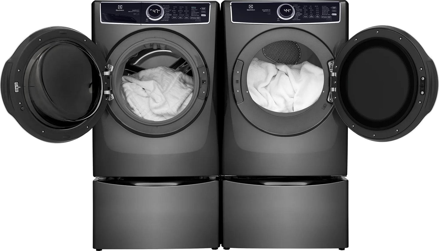 Pair of dark gray front load washer and electric dryer with open doors and white laundry inside in modern laundry room setting