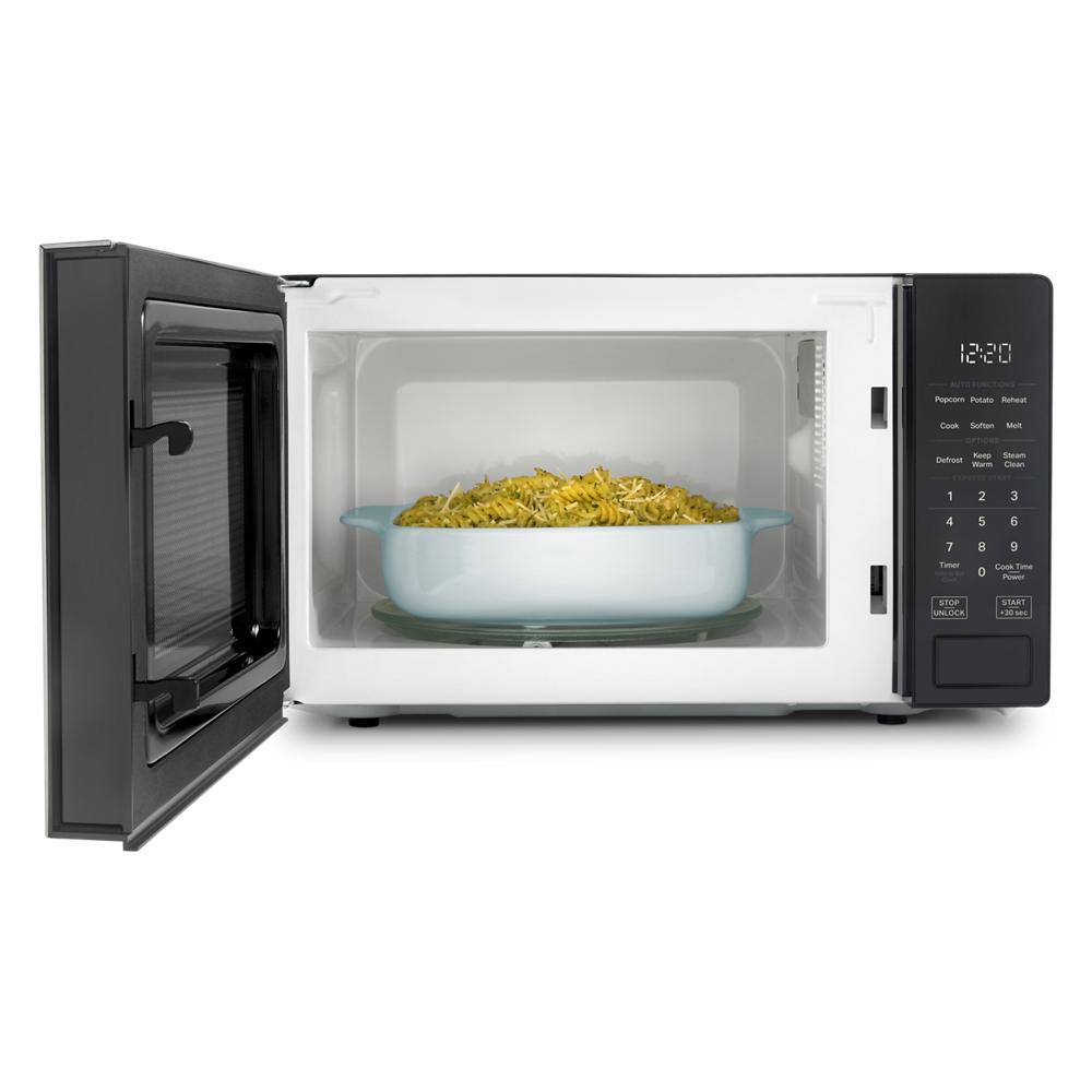 Black countertop microwave with open door, digital control panel, and casserole dish of pasta inside from kitchen appliances collection