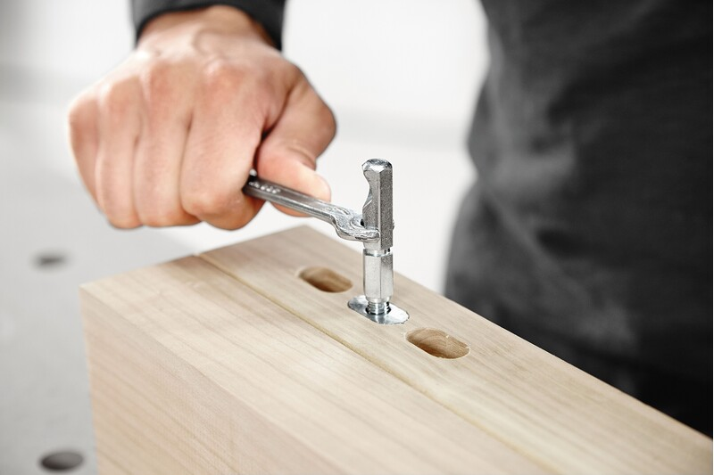 Hand tightening metal anchor bolt with wrench into wood for woodworking tool accessories and home improvement