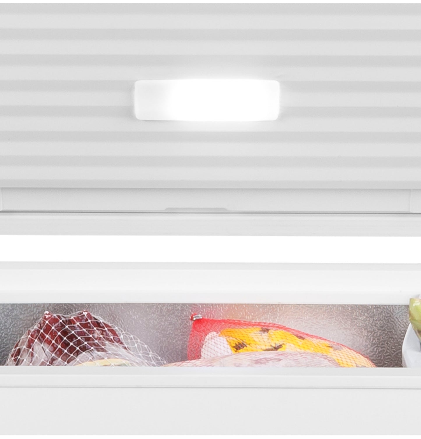 Interior view of chest freezer showing bright interior light and frozen food items inside the storage compartment