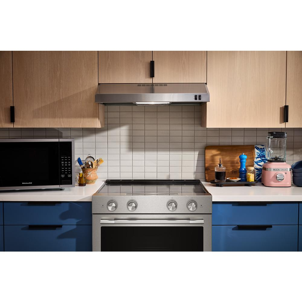 Stainless steel microwave hood with dual fan ventilation mounted over electric range in modern kitchen setting