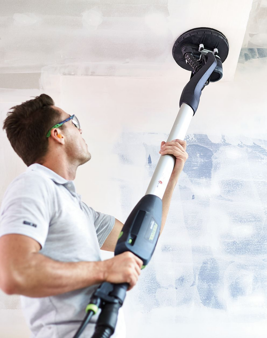 Man using long-handled drywall sander with ergonomic grip smoothing a ceiling for home improvement tasks