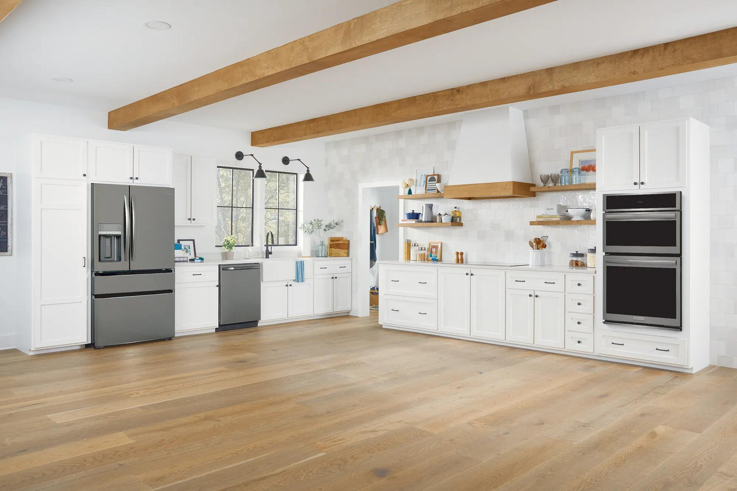 Built-in black stainless steel 27-inch electric wall oven and microwave combo in modern kitchen setting with white cabinetry