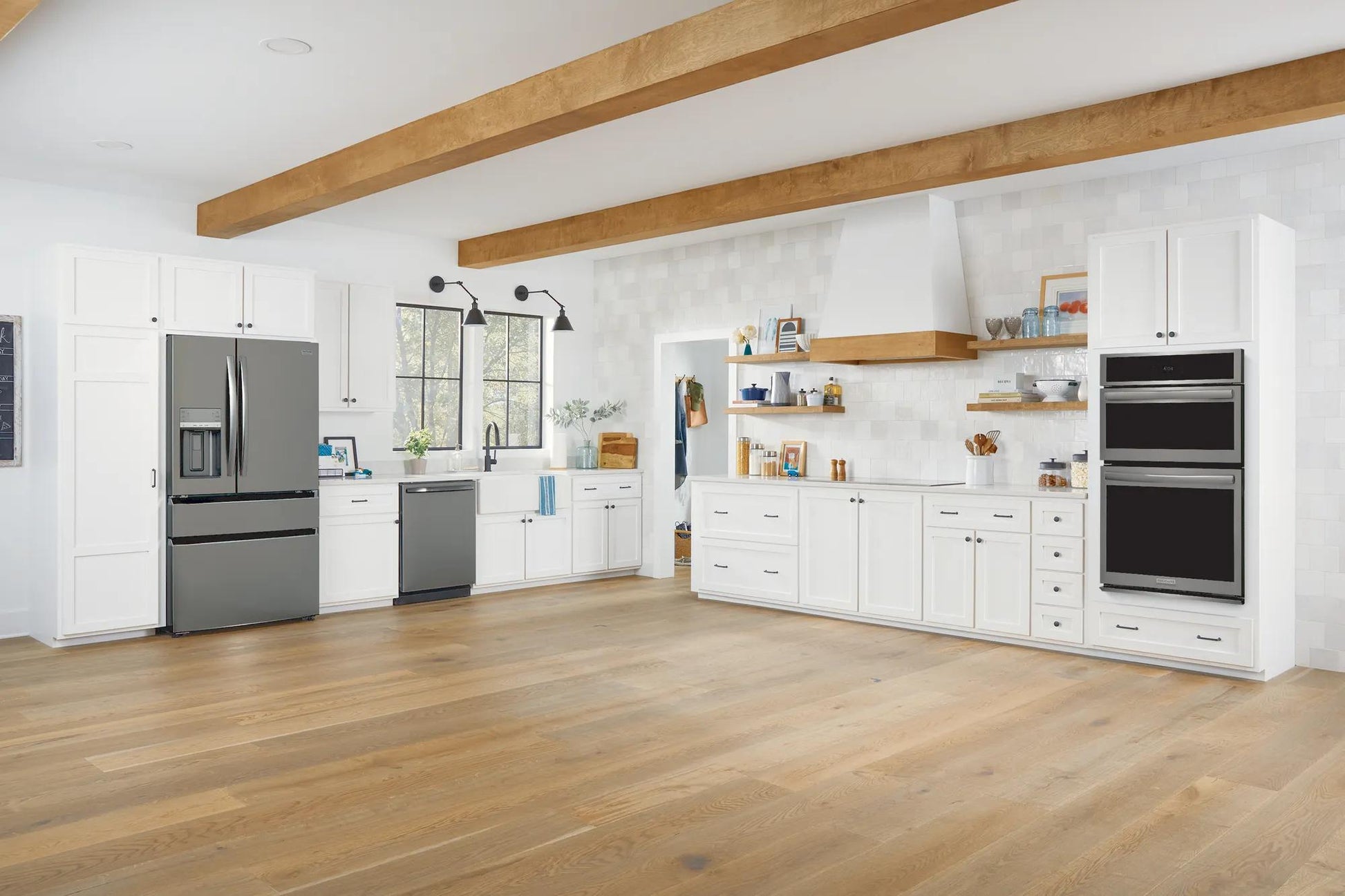 Built-in black stainless steel 27-inch electric wall oven and microwave combo in modern kitchen setting with white cabinetry