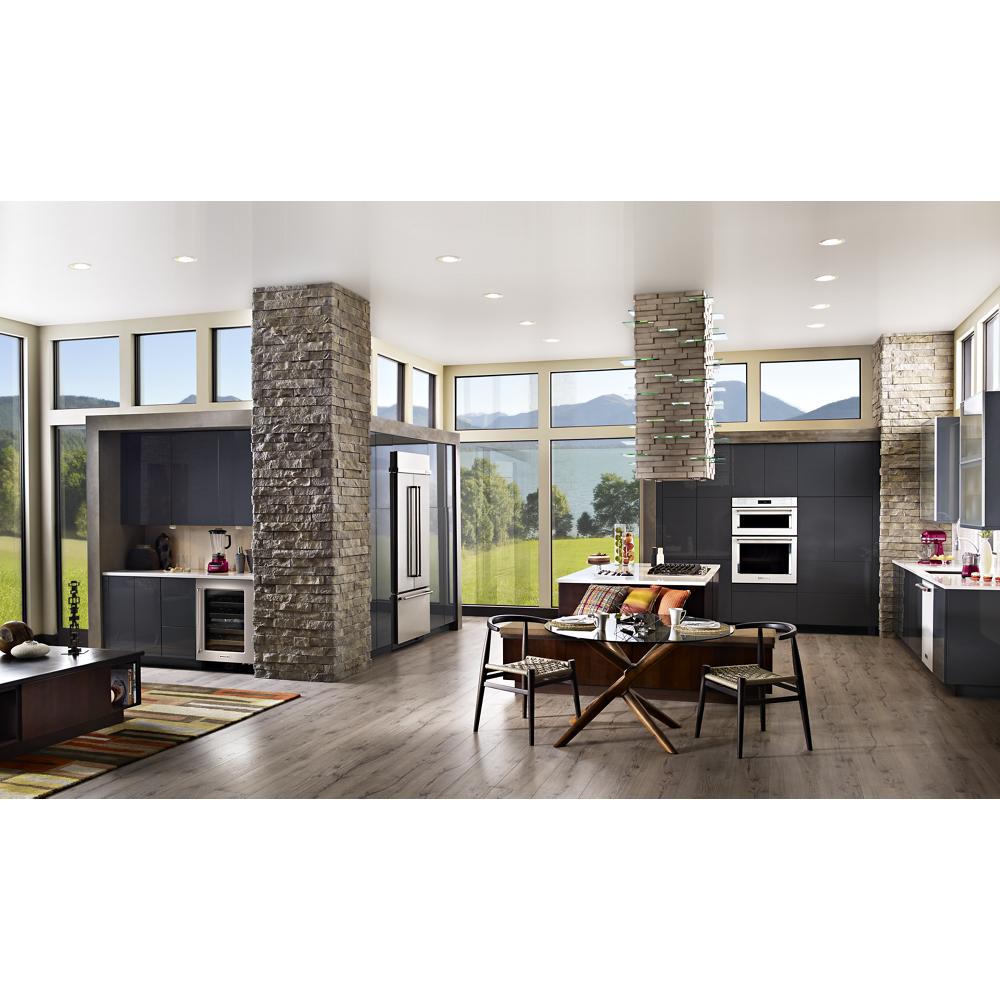 Spacious modern kitchen with stone pillars, floor-to-ceiling windows, dark cabinetry, and a wood floor in home improvement setting