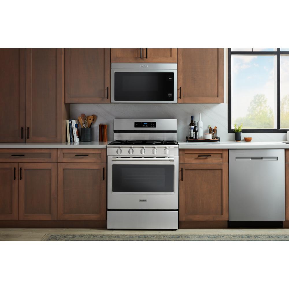 Stainless steel 30-inch gas range with control knobs, digital display, and oven in modern kitchen setting with wood cabinets
