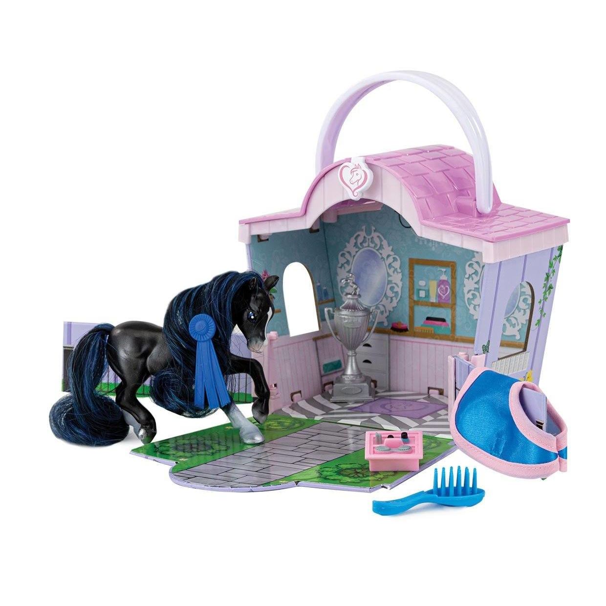 Miniature black horse figurine with blue ribbon next to a pink and purple toy grooming salon set with brush and accessories