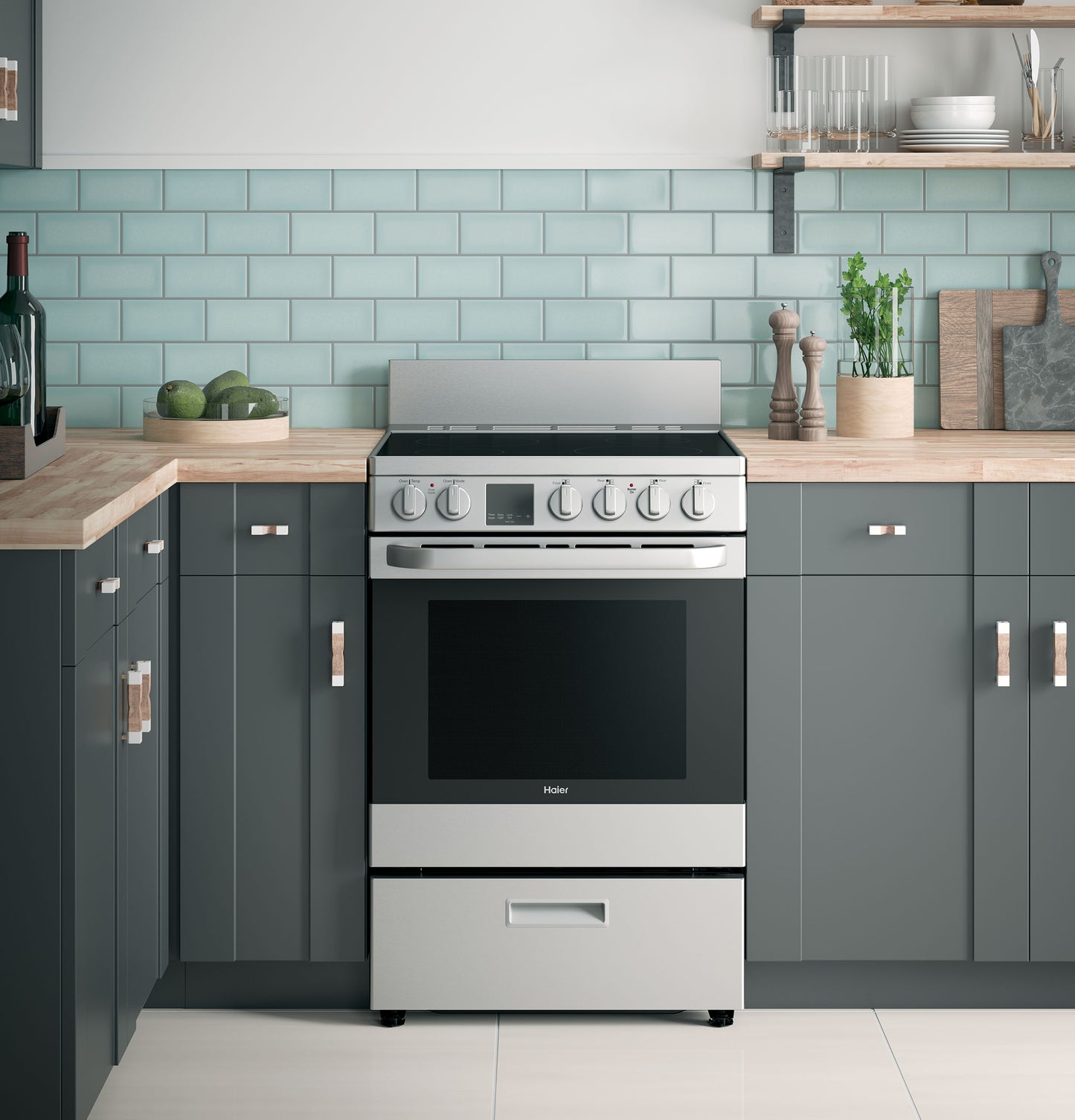 Stainless steel electric range with control knobs and digital display in modern kitchen with gray cabinets and subway tile backsplash