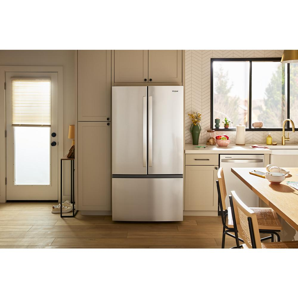 Modern kitchen with stainless steel French door refrigerator, beige cabinets, and hardwood floor in appliances setting