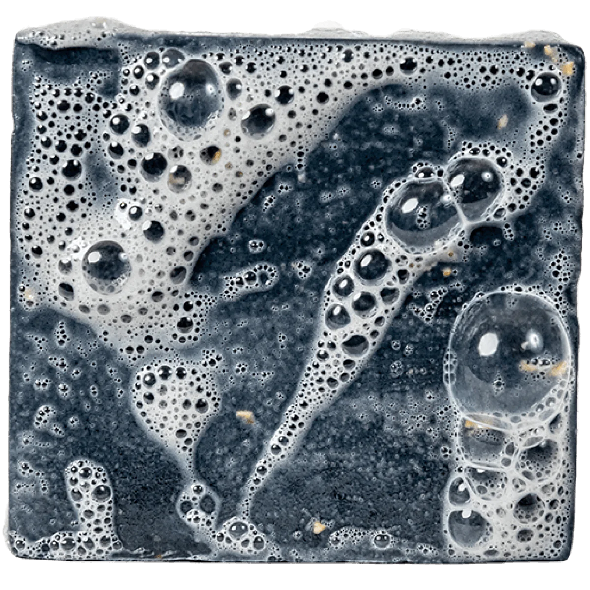 Dark textured soap bar with foamy lather and small natural exfoliating particles on the surface