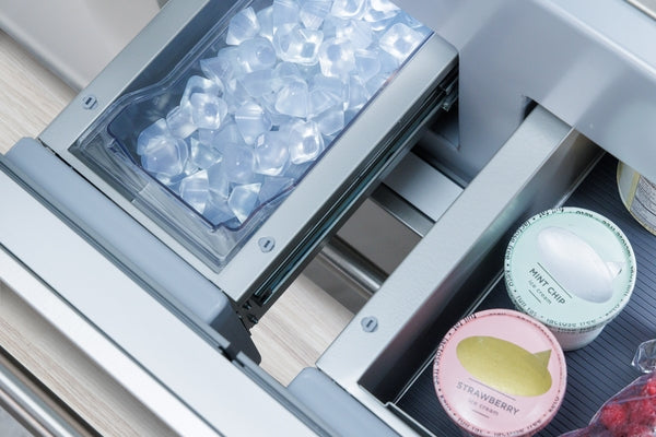 Open built-in bottom freezer drawer with ice bin and organized storage of frozen treats in kitchen appliances collection
