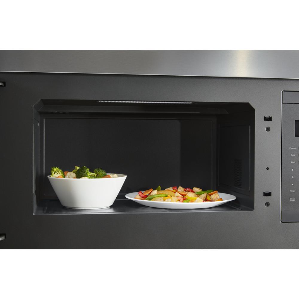 Interior view of over-the-range microwave with two plates of mixed vegetables inside in kitchenware setting