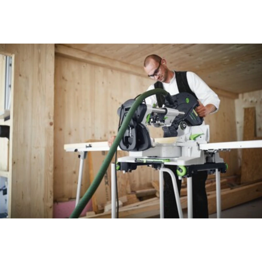 Man operating Festool Kapex miter saw with dust extraction hose in unfinished wood interior for home improvement tools