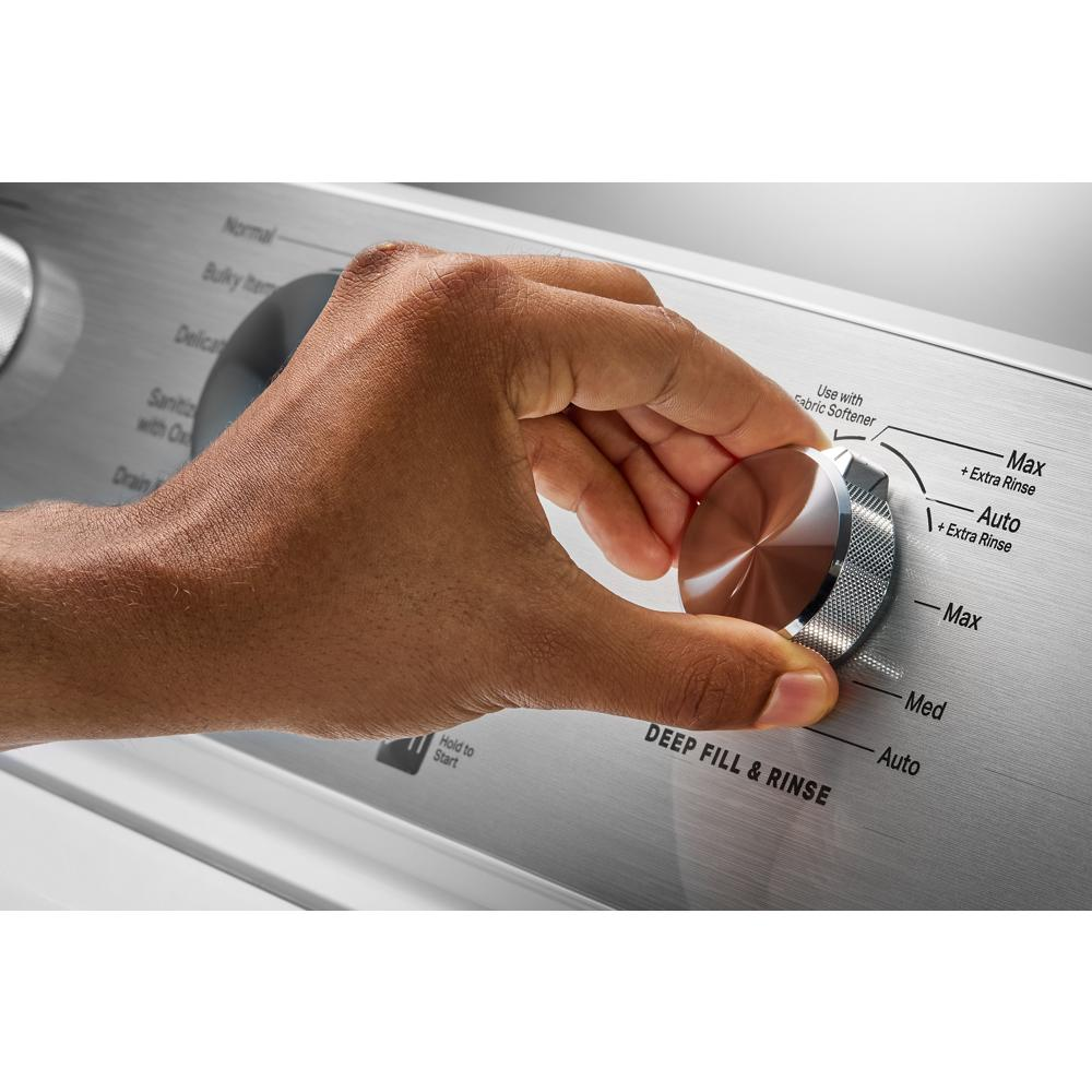 Hand adjusting silver control dial on stainless steel panel of top load washer in washers and appliances collection