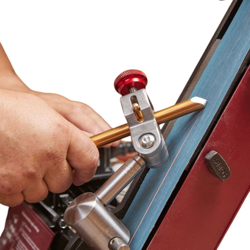 Hand holding a sharpening tool fixture guiding a woodturning accessory on a belt sander in woodworking tools collection