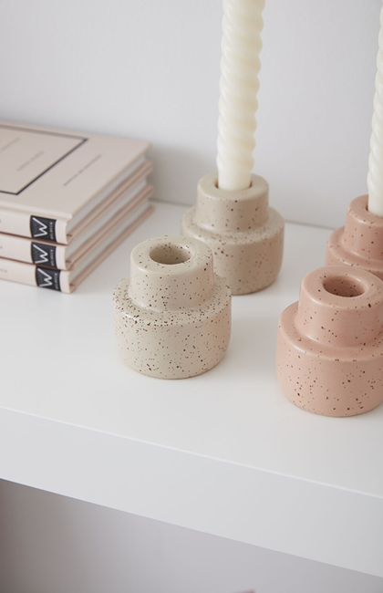 Set of off-white and pink speckled ceramic candleholders with a matte finish styled on a white surface for home accents