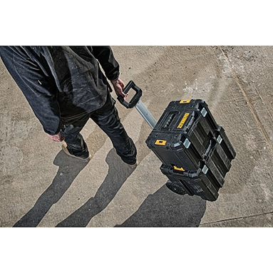 Person pulling a black rolling tool storage box with telescoping handle for workshop organization and tool storage