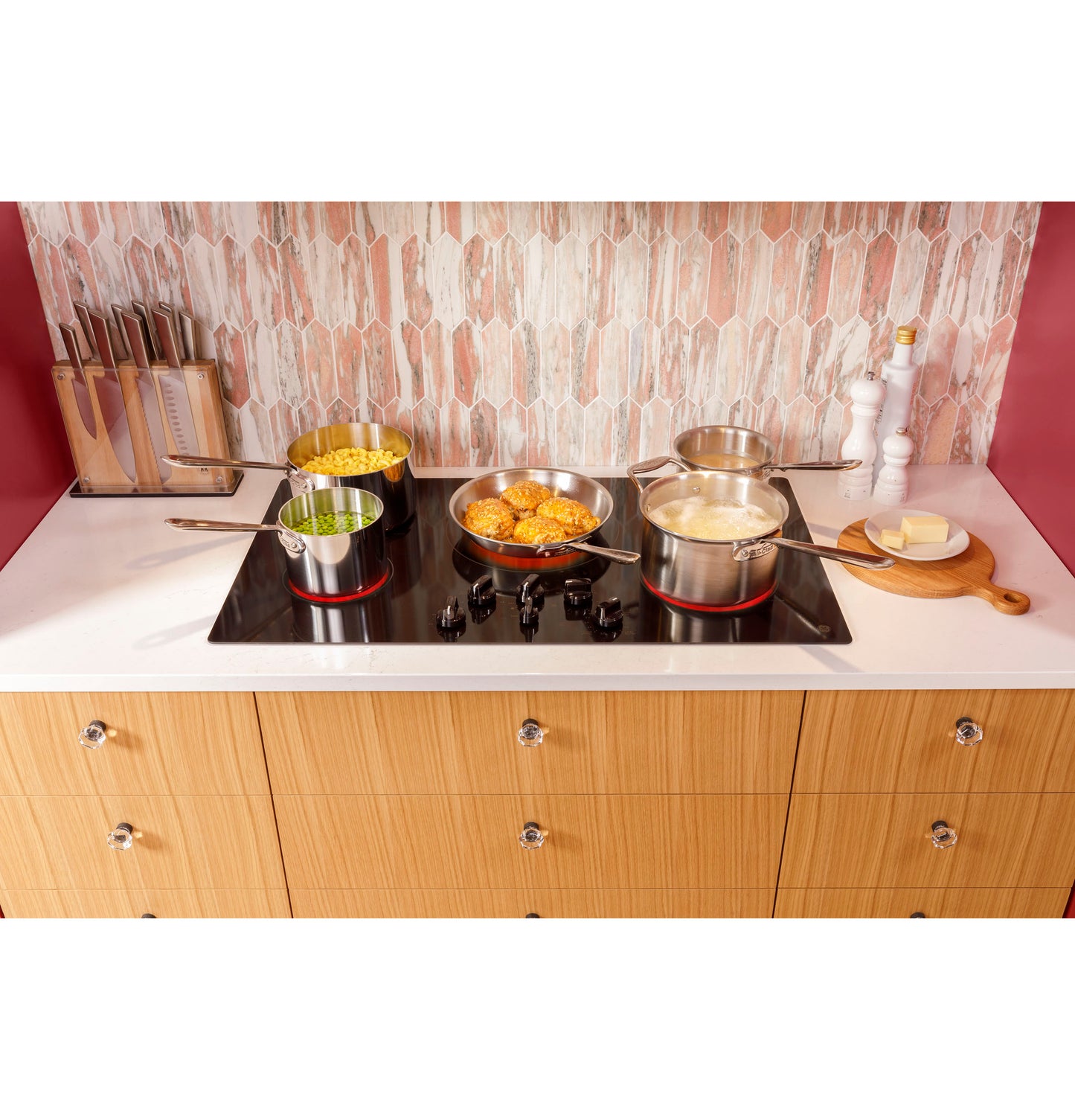 GE electric cooktop with four pots cooking pasta, green beans, meatballs, and boiling water in kitchen appliances setting