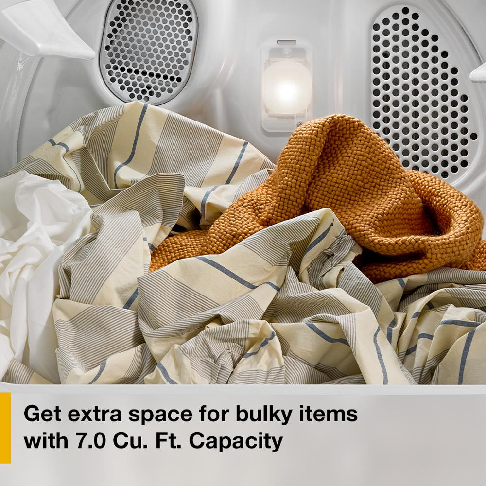 Inside view of vented electric dryer drum with bulky linens and knitwear highlighting large 7.0 cu. ft. capacity