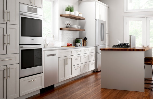 Modern kitchen featuring stainless steel built-in ovens, gas cooktop on island, white cabinetry, and hardwood flooring