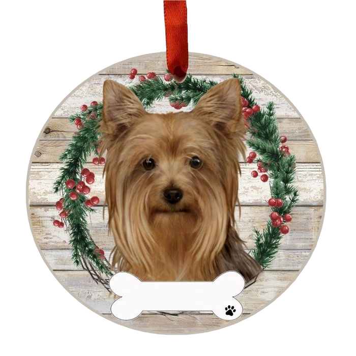 Round Christmas ornament featuring a Yorkie face with wreath and red berries on rustic wood background