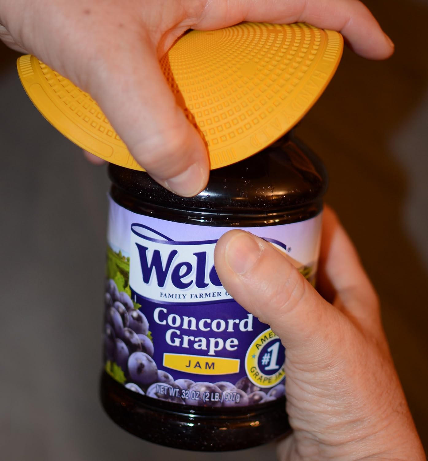 Hand using yellow textured grip pad to twist open a jam jar lid in kitchenware and home improvement tools collection