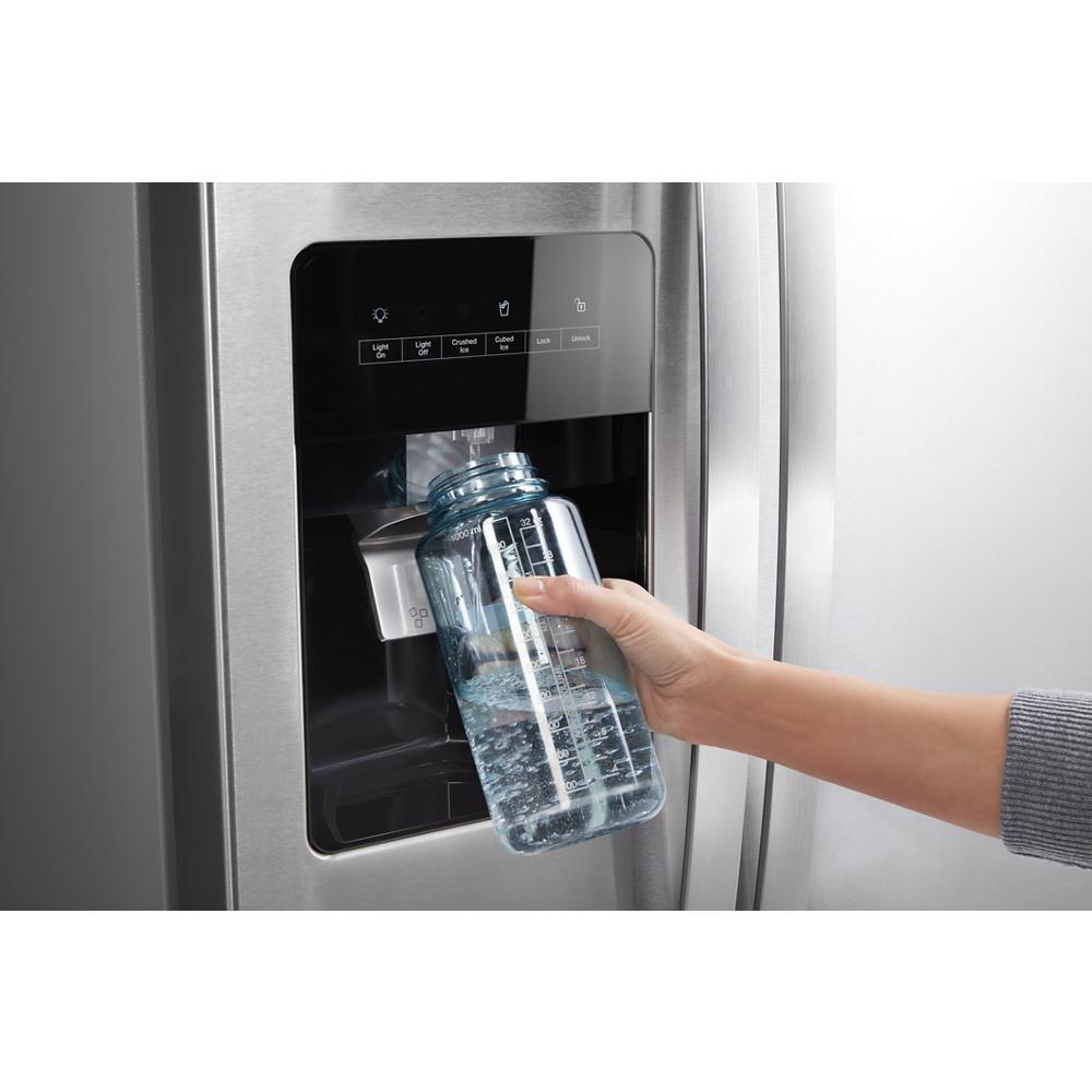 Hand filling clear bottle with water from stainless steel side-by-side refrigerator water dispenser in appliances collection