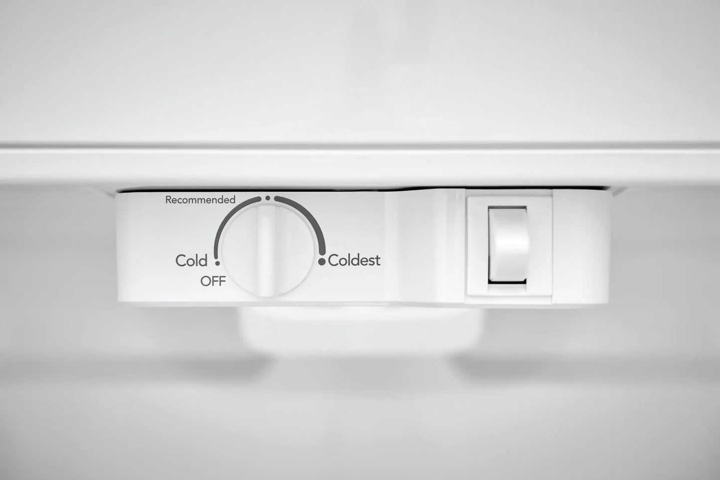 Close-up of white temperature control dial and light switch inside a top freezer refrigerator in appliances collection