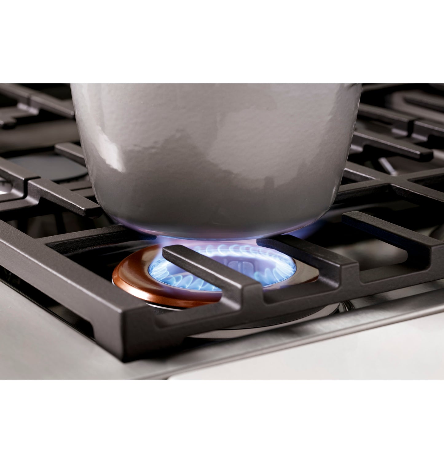 Close-up of lit burner with blue flame heating pot on smart all-gas commercial-style range in modern kitchen setting