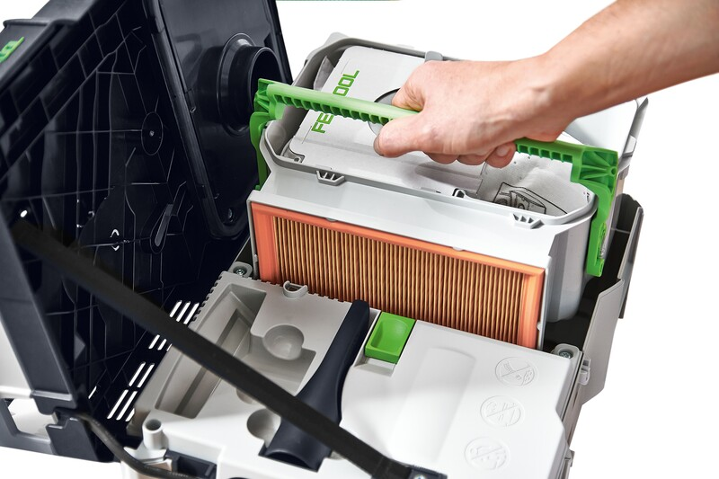 Hand removing rectangular pleated air filter with green handle from a tool dust extraction system housing for maintenance