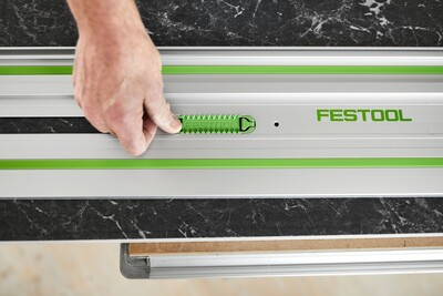 Hand placing green adhesive pad onto aluminum guide rail for woodworking tools and home improvement accessories.