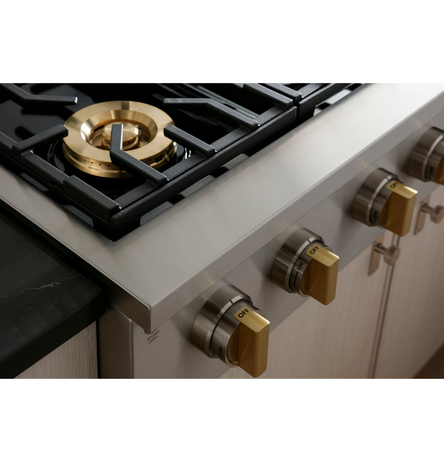Close-up of stainless steel gas rangetop burner with gold-tone control knobs in Cooktops and Kitchen & Kitchenware collections