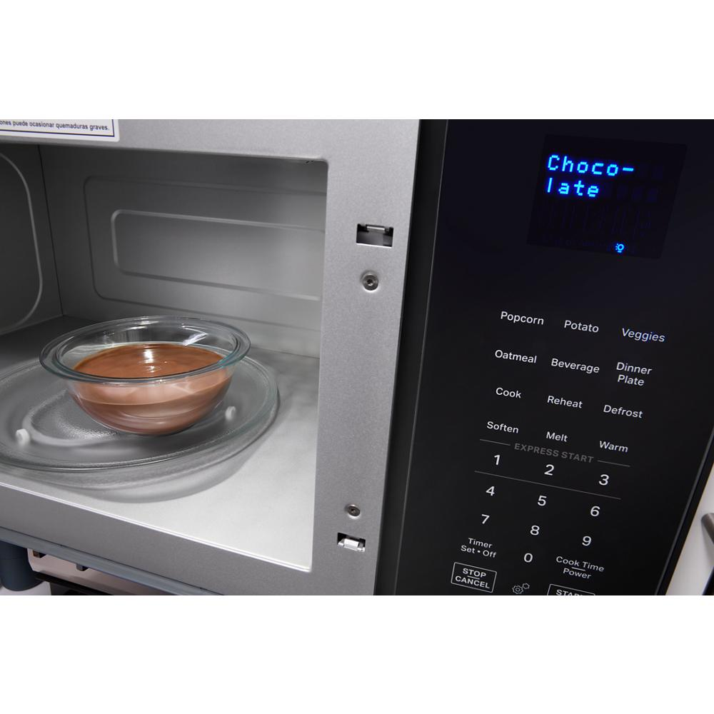 Close-up of a microwave interior with a bowl of melted chocolate and digital sensor cooking controls visible on the panel