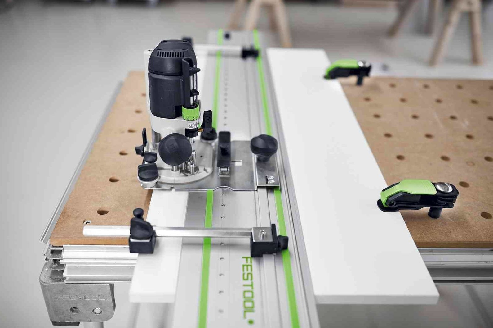 Festool hole drilling guide clamped to workbench with drill and wood panel for precise cabinet making tasks