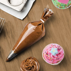 Single disposable pastry icing bag filled with chocolate frosting beside decorated cupcakes on wooden surface