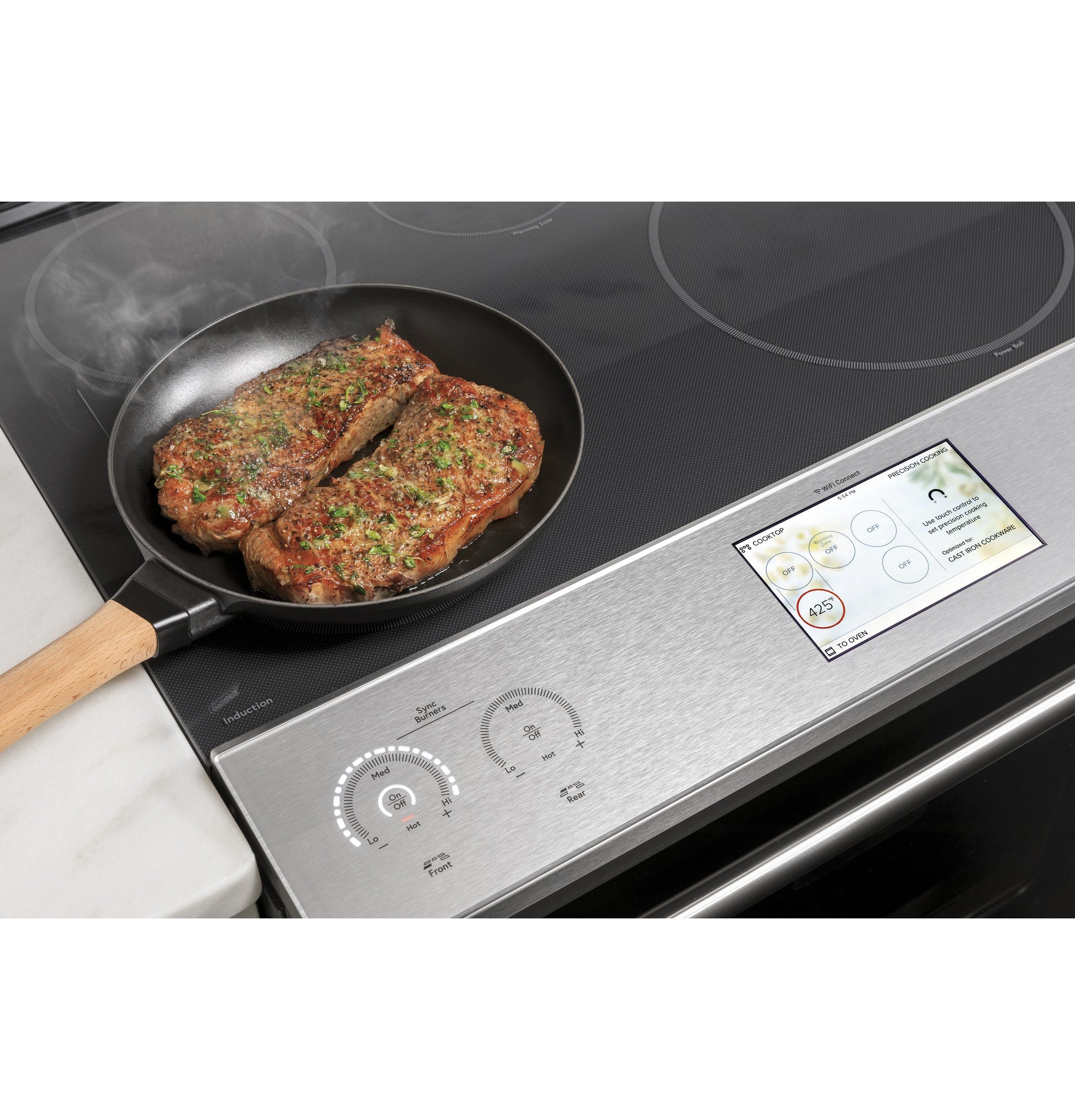 Seasoned steaks sizzling in skillet on platinum glass induction cooktop with digital touch controls and display