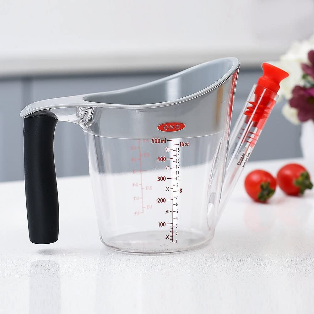 Clear fat separator with black handle, red stopper, and measurement markings for kitchenware and gadgets collections