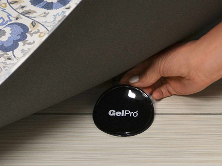 Hand placing black GelPro Gelly Grippers anti skid pad under bath or kitchen rug on wooden flooring under $50 collection