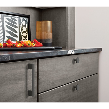 Matte black cabinet pull and round knob on gray cabinets in modern kitchen hardware and furniture accessories collections