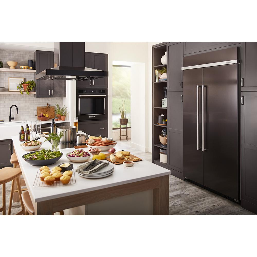 Modern kitchen with dark cabinetry, stainless steel appliances, and a white island featuring fresh meals and tableware