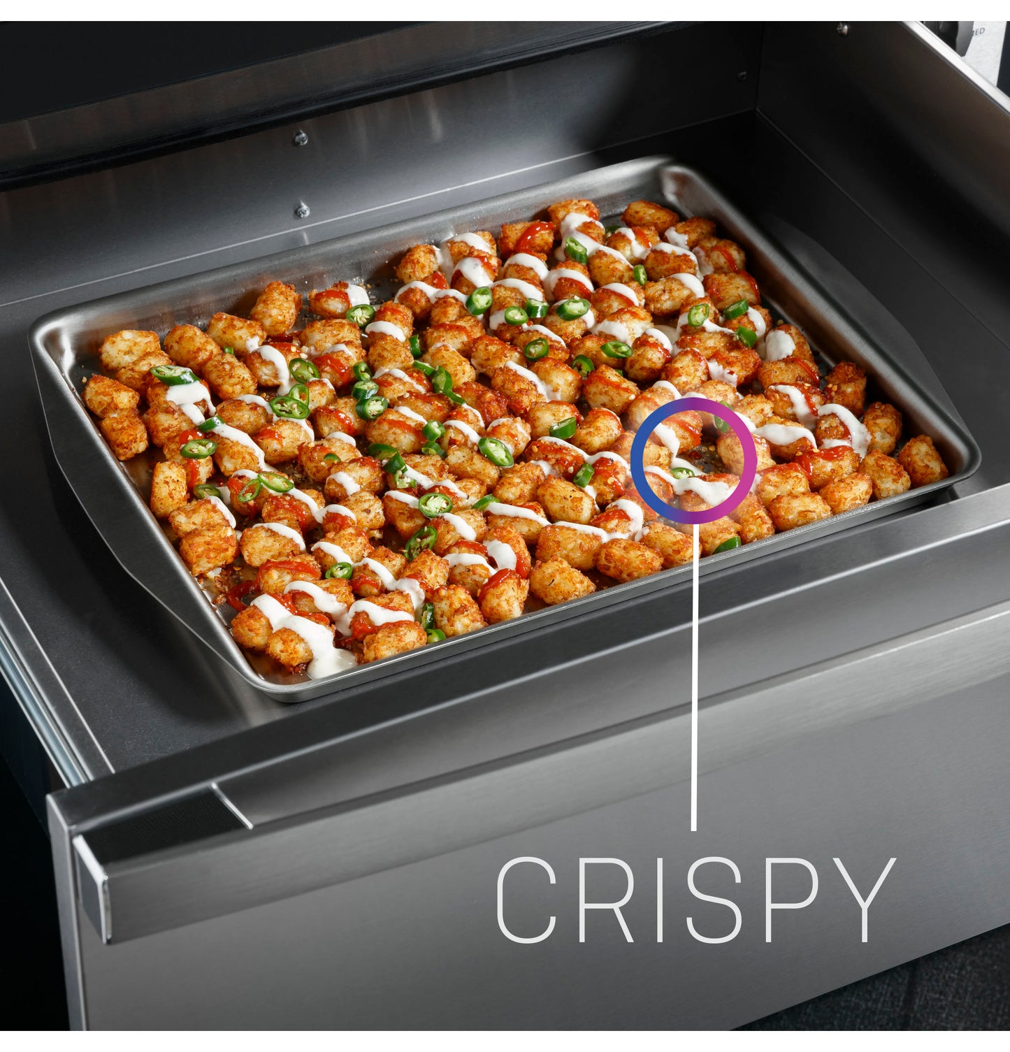 Sheet pan of crispy seasoned tater tots with drizzled sauce inside a stainless steel warming drawer appliance