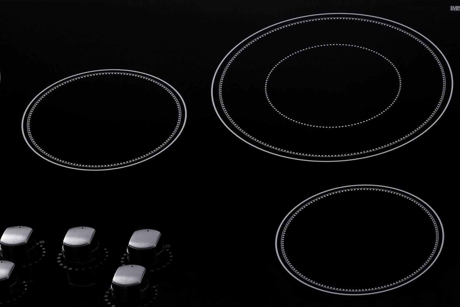 Black smooth glass radiant cooktop with five burners and four metallic control knobs from kitchen appliances collection