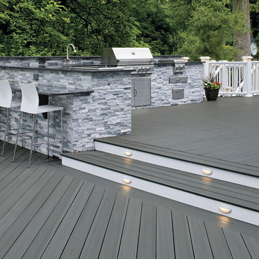 Outdoor deck featuring durable gray capped composite deck boards and riser boards with built-in step lighting