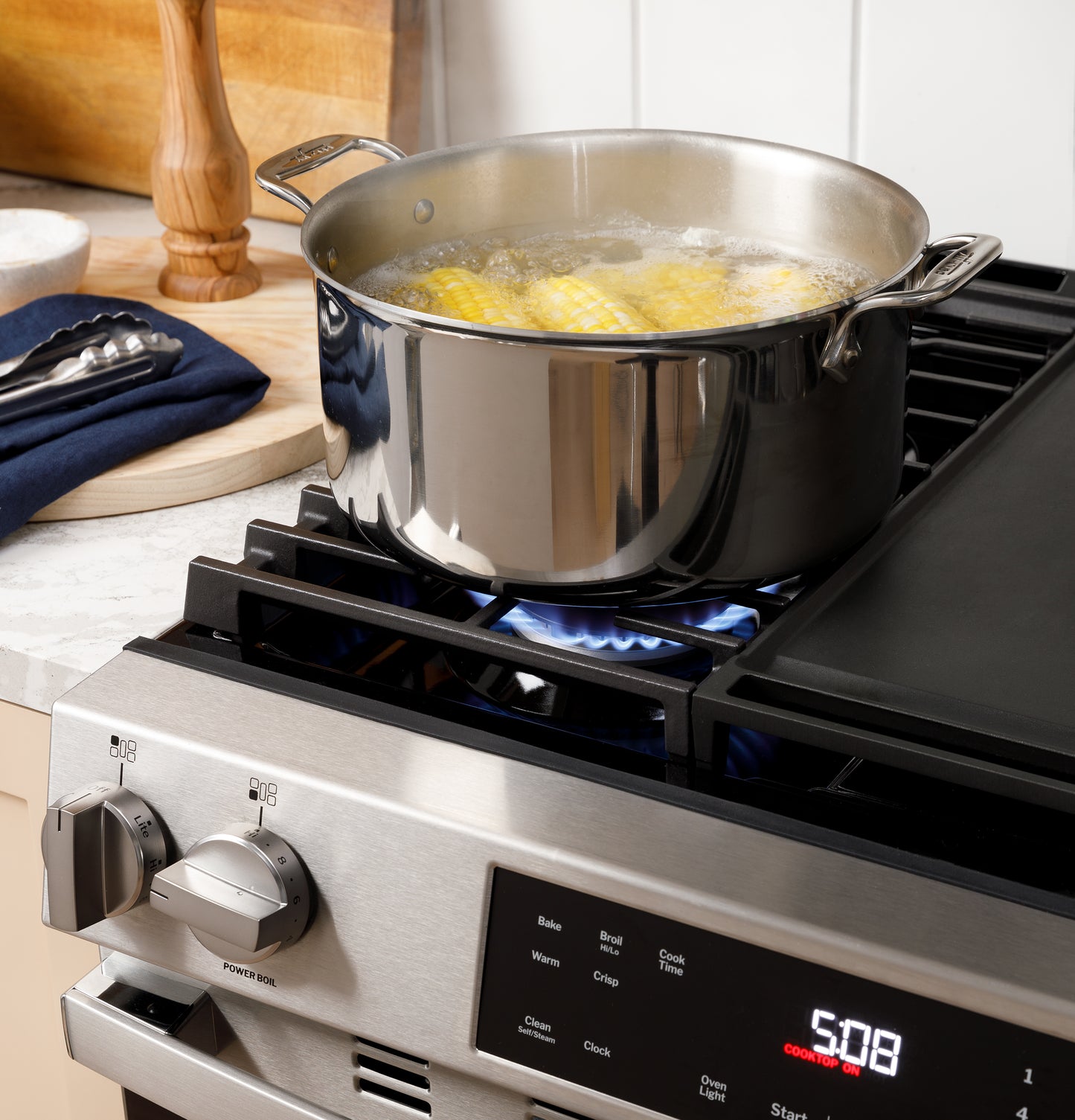 Stainless steel pot boiling corn on gas burner of slide-in front control range in kitchen setting