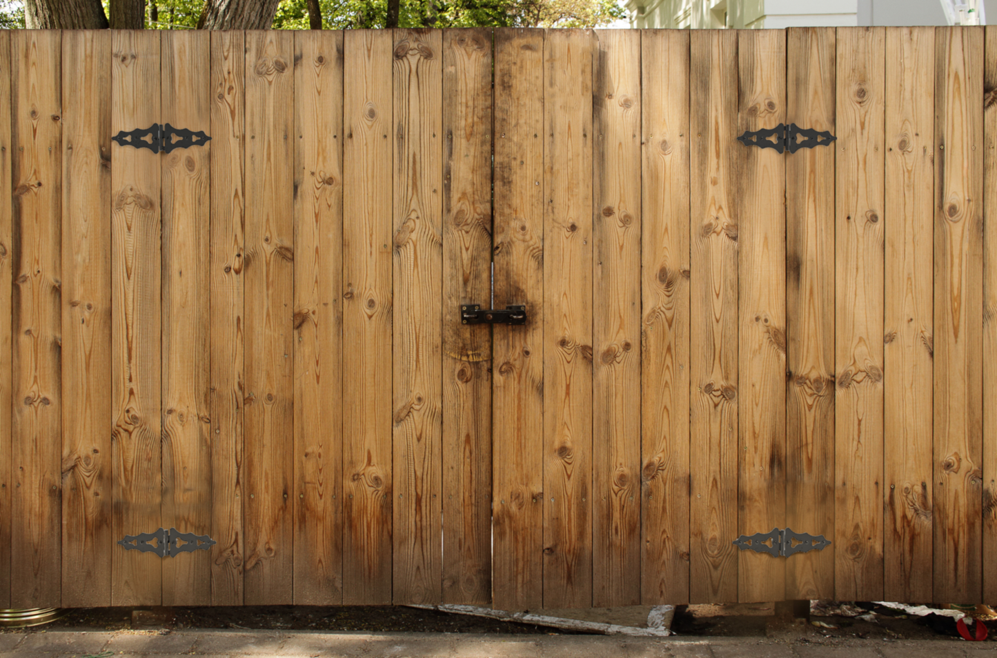 Two black ornamental S-hinges mounted on natural wood gate for gate hardware and home improvement tools under $50
