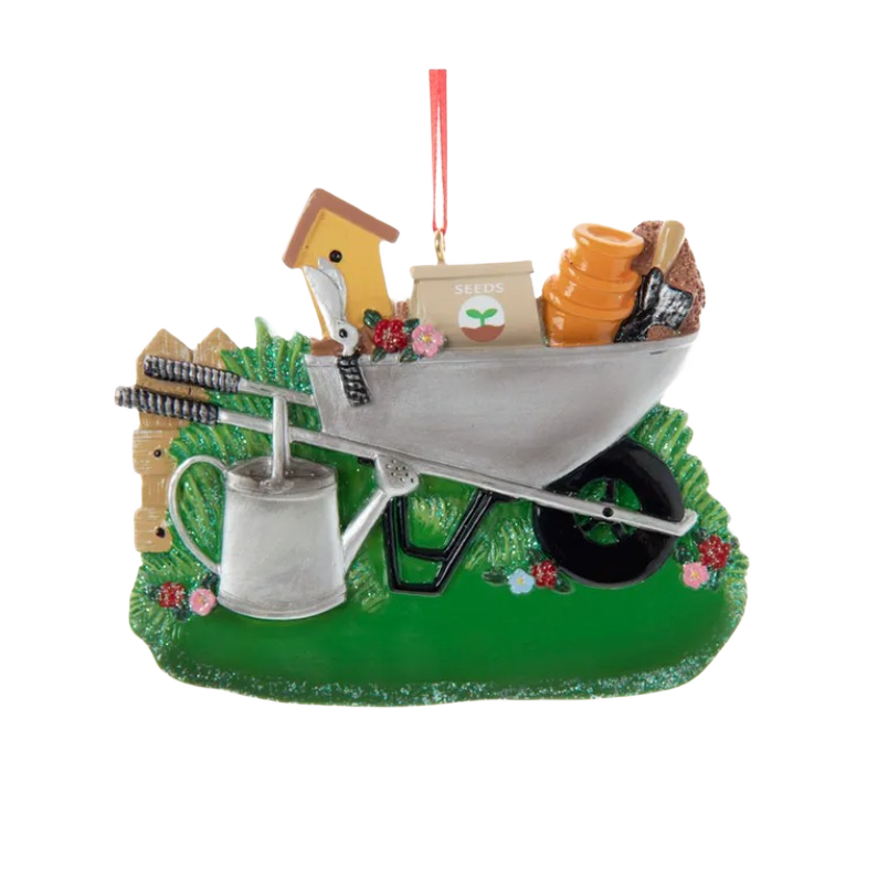 Wheelbarrow ornament with gardening tools, seed packet, and watering can on green grass base for Christmas décor under $50