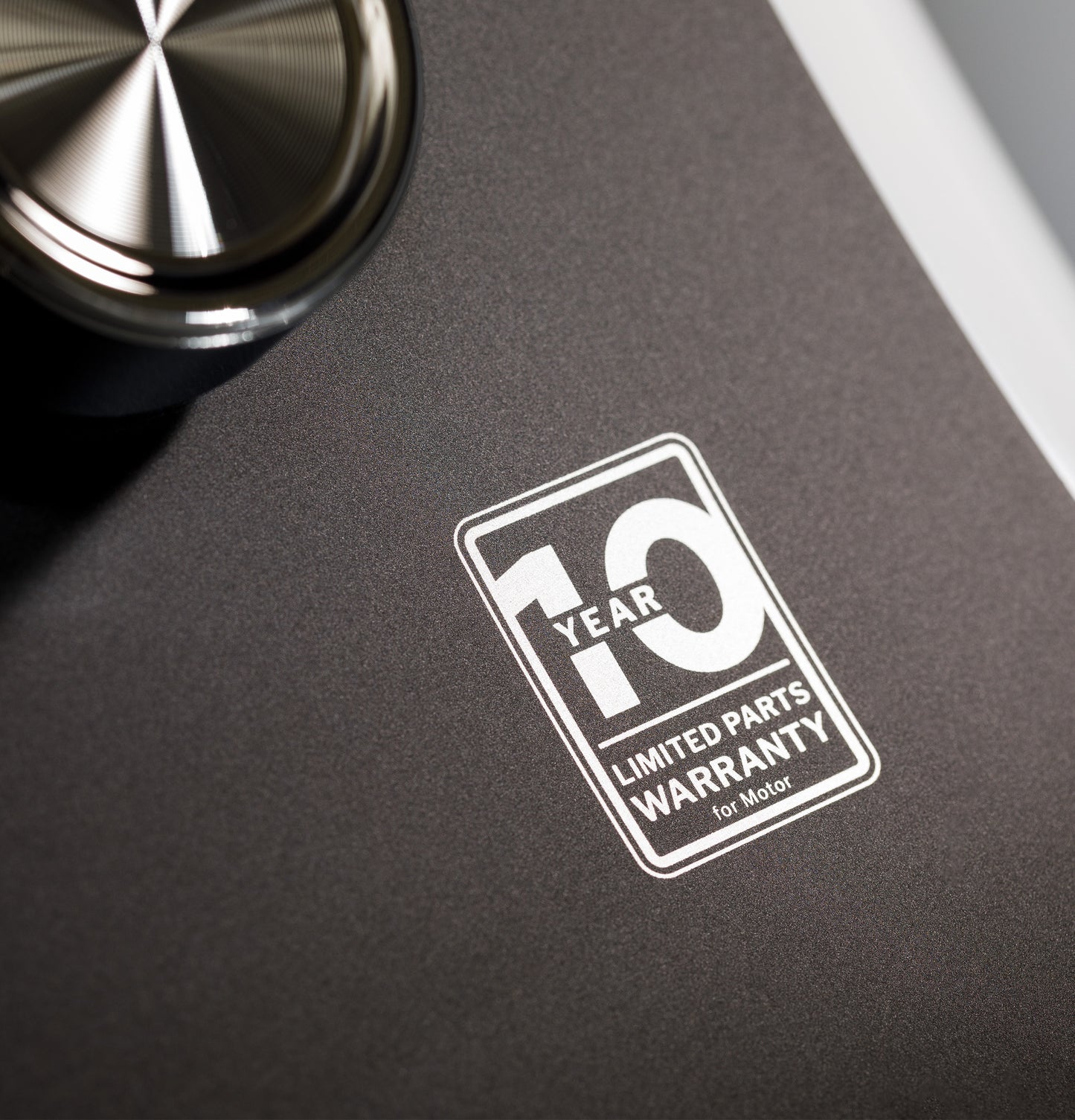 Close-up of a washer control panel showing a 10-year limited parts warranty label for motor protection