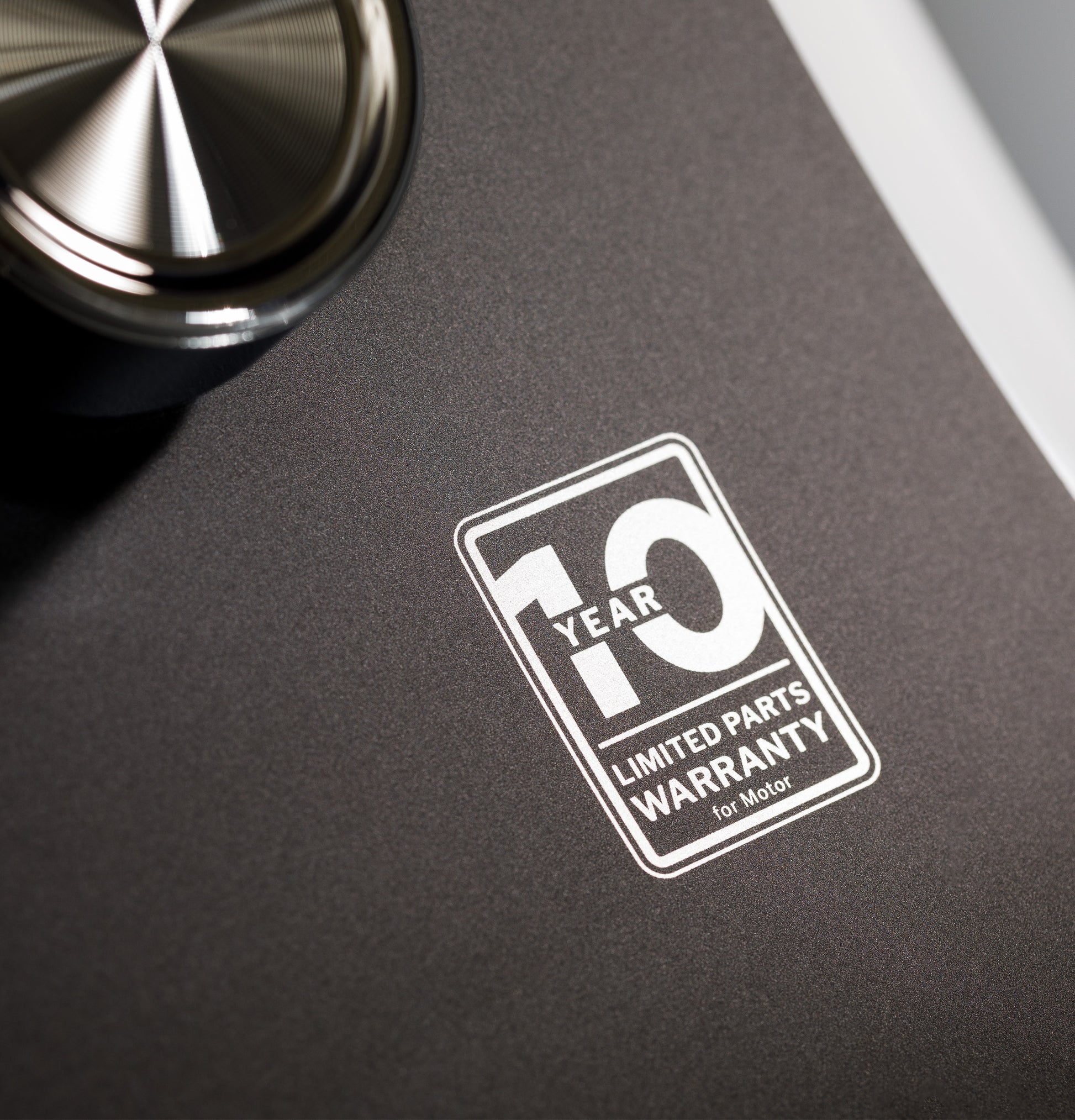 Close-up of a washer control panel showing a 10-year limited parts warranty label for motor protection
