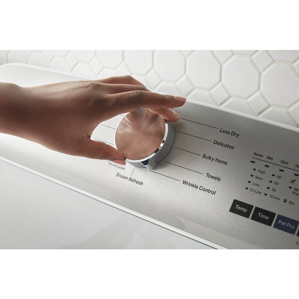Hand adjusting cycle selector knob on silver control panel of top load electric dryer in laundry area