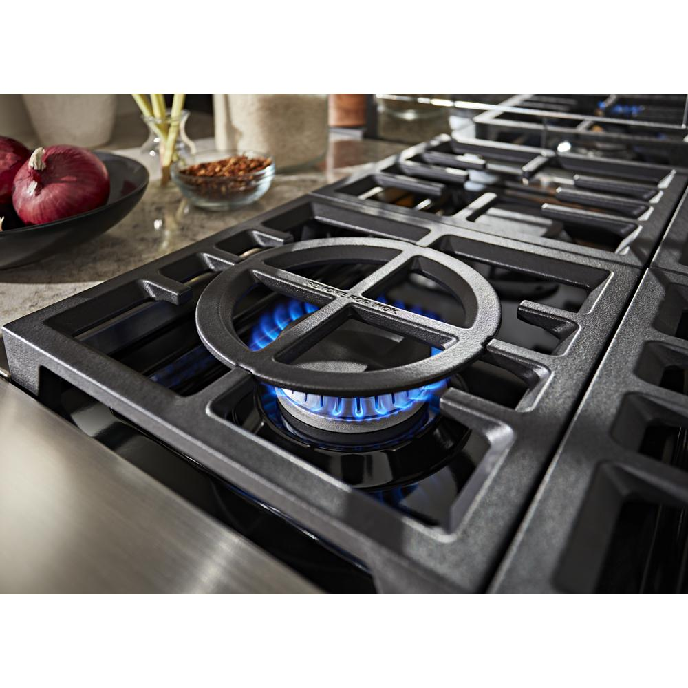 Close-up of cast iron burner grate with blue flame on gas cooktop from KitchenAid range in kitchenware collection